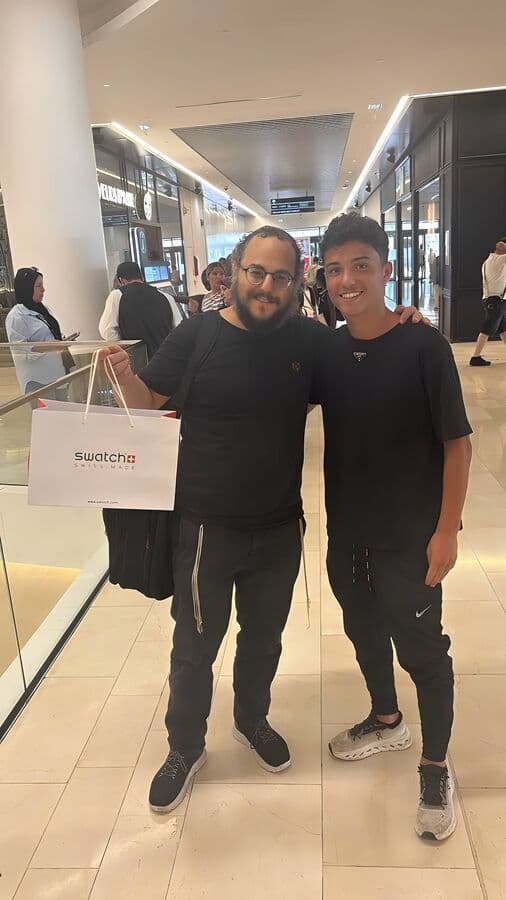 Lévi Siboni, gagnant du concours Montre, avec un membre de l'équipe GoldenChance dans un centre commercial, sac Swatch en main